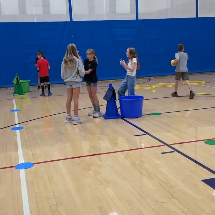Students coordinate pool noodles in a cooperative challenge