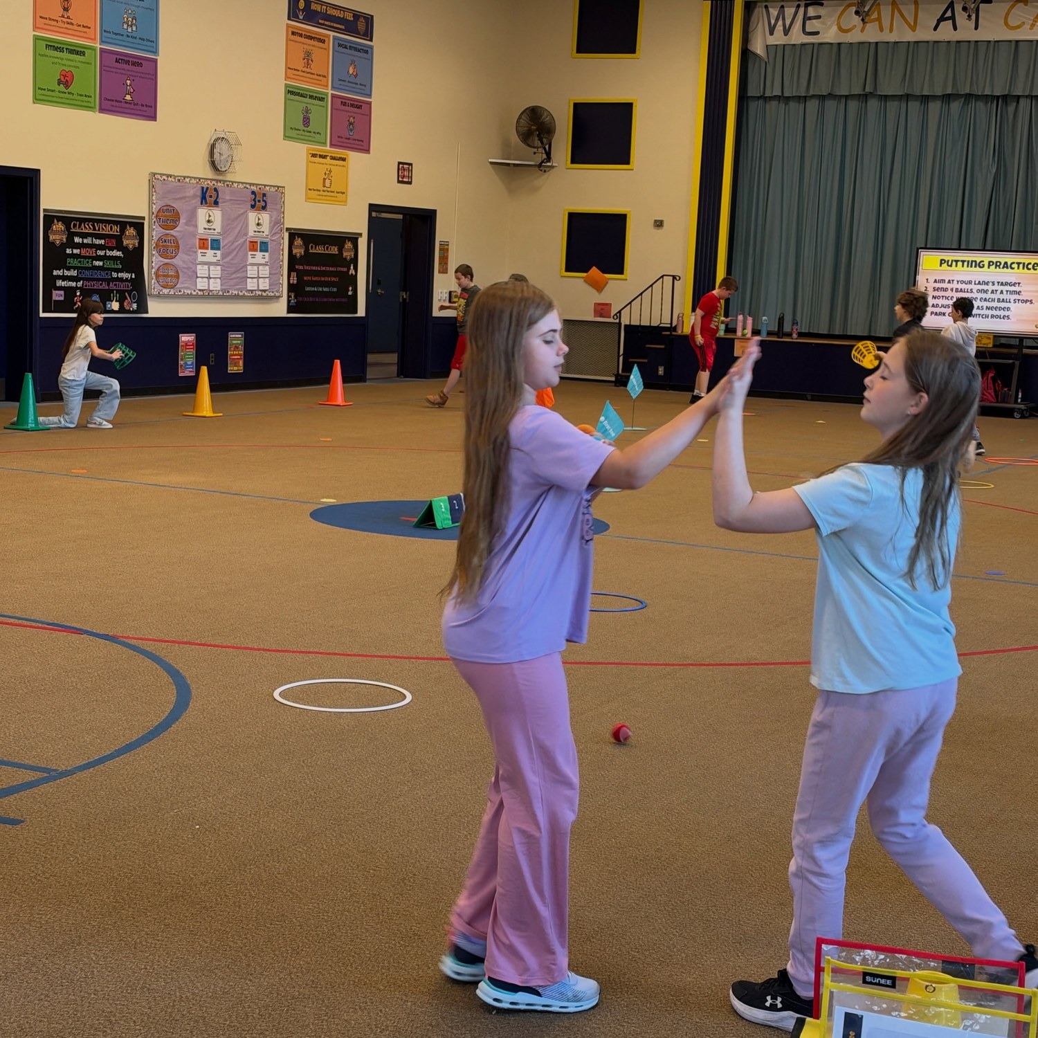 Students celebrate progress with a high-five during a golf lesson